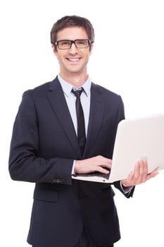 Quality support for your business. Handsome young man in formalwear working on laptop and smiling while standing isolated on white background photo