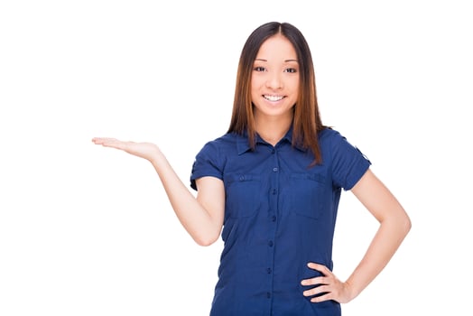 Copy space in her hand. Cheerful young Asian woman holding a copy space and smiling while standing isolated on white photo