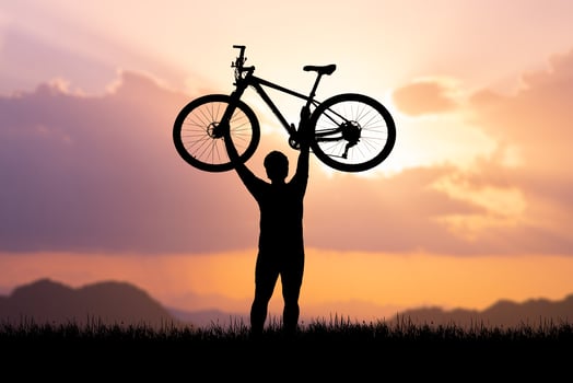 Man holds a bicycle on top of a mountain. concept of success and victory photo