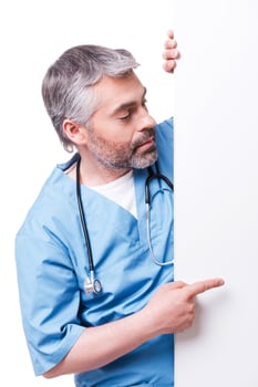 Surgeon pointing copy space. Confident mature surgeon pointing copy space while standing isolated on white photo
