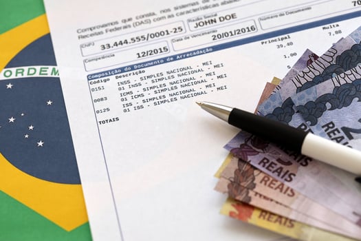 Brazilian proof of collection report with brazilian reals money bills and pen on national flag background. Brazilian legal taxpaying and tax reporting photo