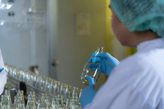 Product quality control officer in fruit juice production line Carry out an inspection of bottles used to contain fruit juices photo