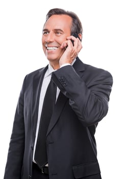Good business talk. Happy mature man in shirt and tie talking on the mobile phone and smiling while standing isolated on white background photo