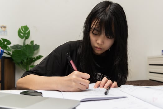 Asian student girl is writing homework and reading book at desk photo