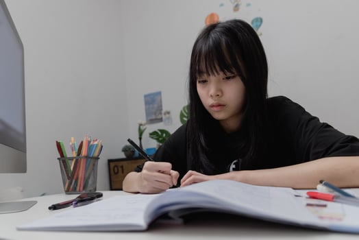 Asian student girl is writing homework and reading book at desk photo