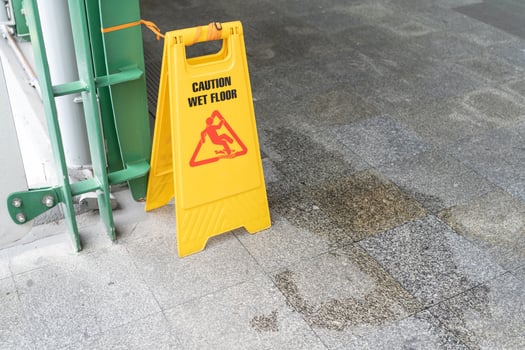 Yellow Caution slippery wet floor sign on the wet ground photo
