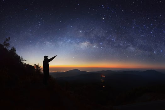 A Man is standing next to the milky way galaxy pointing on a bright star at Doi inthanon Chiang mai, Thailand. photo