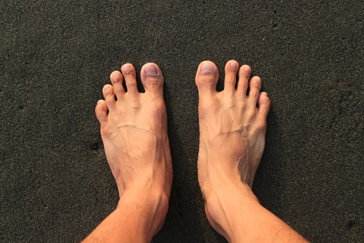 Two foot on the beach. with brown black sand beach photo