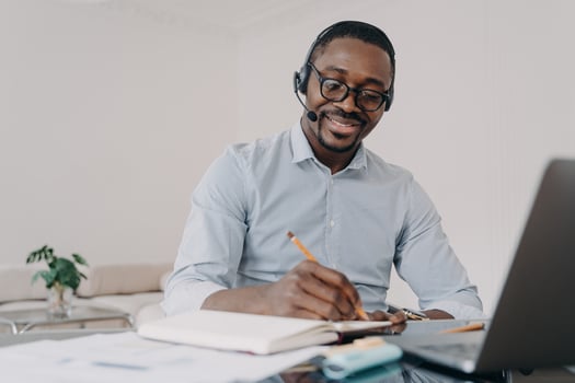 African american man in headset learns online at laptop, takes notes. Elearning, distance education photo