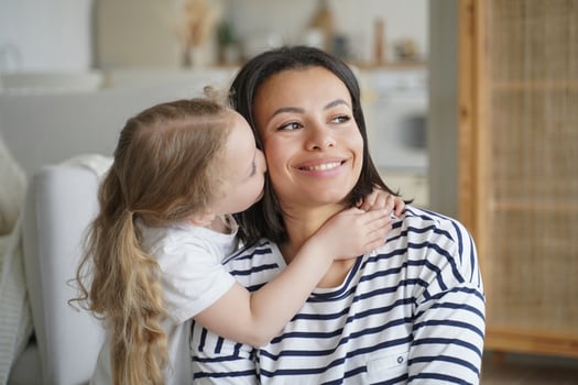 Portrait of family, kid hugs and kisses mom. Mother is smiling. Concept of affection and motherhood. photo
