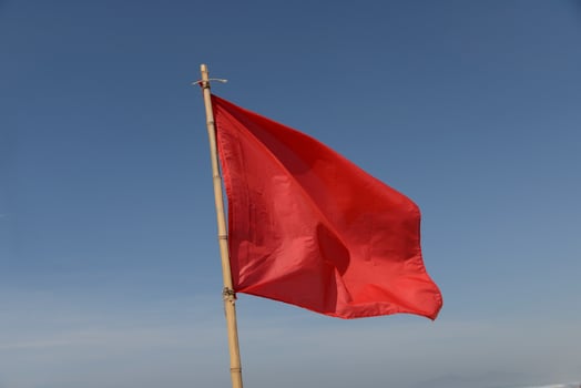 red flag swaying in the wind on a blue sky background photo