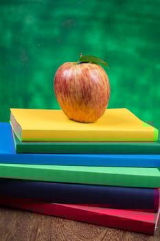 Apple fruit on top of a book stack, on the back of school classes. photo