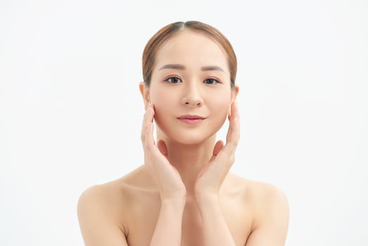 Portrait of young beautiful Asian woman touching her face with naked body over white background. photo