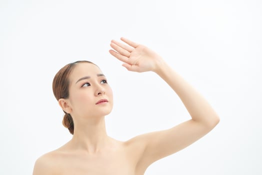 Portrait of young Asian woman looking to the side and showing hand on white background. photo