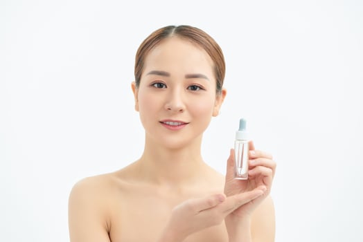 Beautiful young Asian woman showing skin care product isolated on white background. photo