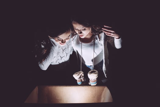 Sisters opens a box with a Christmas present and fascinated looks inside photo