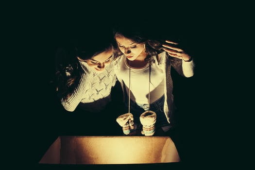 Sisters opens a box with a Christmas present and fascinated looks inside photo