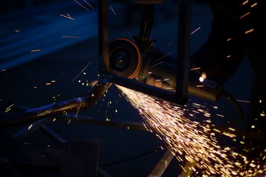 Sparks from grinding metal. Steel processing in workshop. Lights in dark. Production of parts. Cutting became grinder. photo