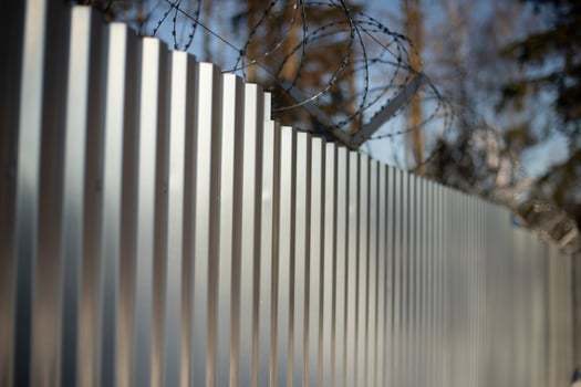 Steel fence with barbed wire. Fencing of territory. Industrial zone. Stainless steel. photo