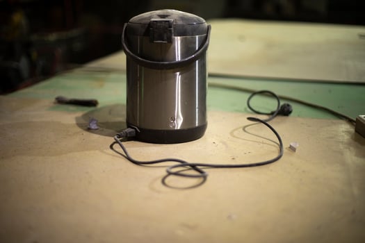 Old thermos. Electrical equipment on table. Boiler for warming water. photo