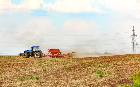 An agricultural tractor with a trailed seeder cultivates the soil in the field by applying the necessary fertilizers. photo