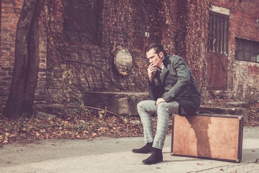 Distraught man sitting on old leather suitcase while contemplating. photo