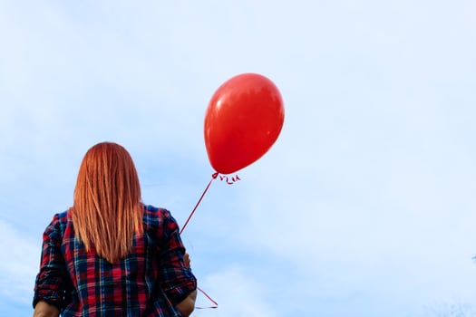Rear view of woman with red balloon against the sky. photo