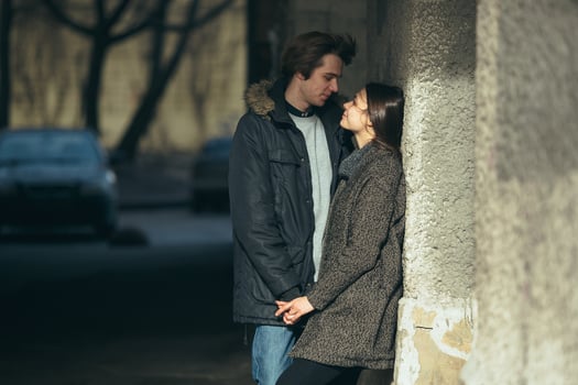 young couple standing together in front of wall photo
