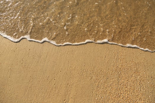 Close Up soft wave flow beautiful ocean on sandy beach. Background. sunshine in the evening. top view. photo