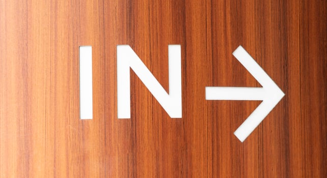 Brown wooden wall with message IN and white arrow photo