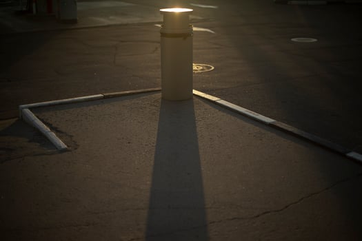 Urn in parking lot. Place to collect garbage on street. Shade from garbage on asphalt. photo