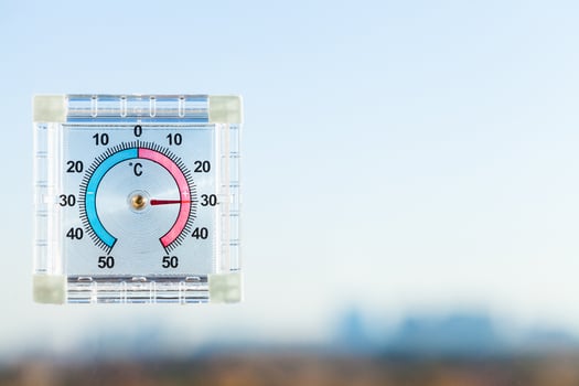 thermometer on home window and blurred skyline photo