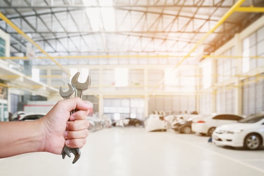 mechanic holding wrench over car repair service centre photo