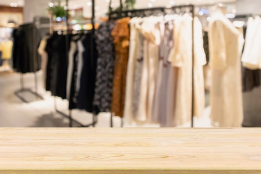 Empty wood table with woman fashionable boutique clothing store window display in shopping mall photo