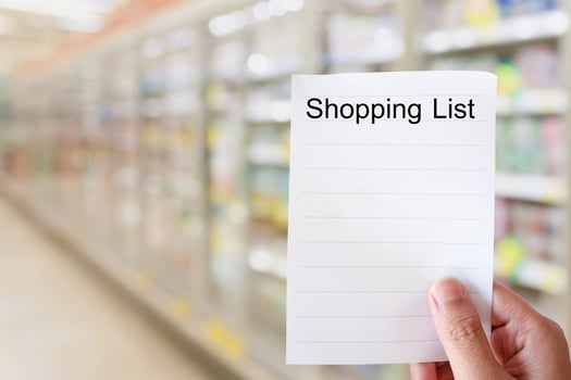 hand hold shopping list paper over supermarket aisle photo