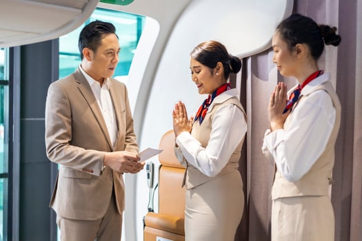 Flight attendant is welcoming and checking passenger boarding pass in business class and show the way to his seat for airplane flight and airline transportation photo