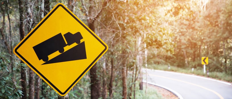 Traffic sign, beware of trucks on a curved road photo