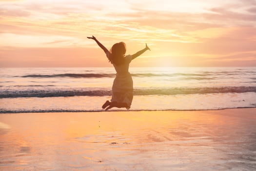 Young woman jumping on the beach at beautiful sunset, Summer vacation concept photo