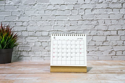 June 2022 white calendar with potted plant on wooden desk. photo