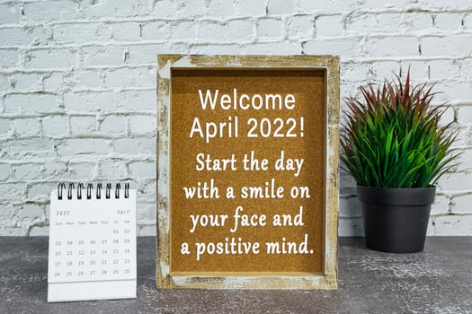 Motivational and inspirational quote on wooden frame with April 2022 calendar. photo