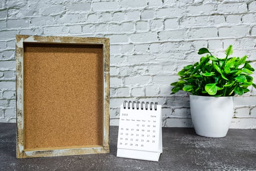 June 2022 white calendar with wooden frame and potted plant on wooden desk. photo