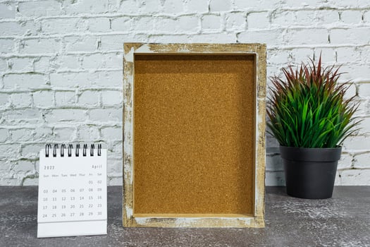 April 2022 white calendar with wooden frame and potted plant on wooden desk. photo
