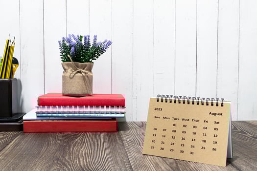 Brown August 2023 calendar on wooden desk with office stationery. photo