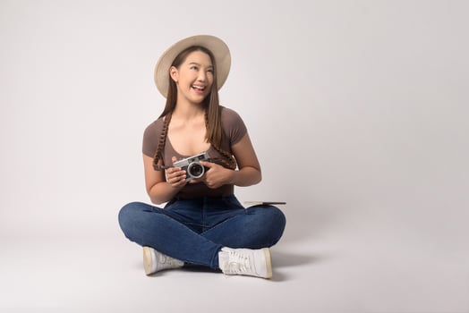 Young happy asian tourist woman over white background studio, travel and holidays concept. photo