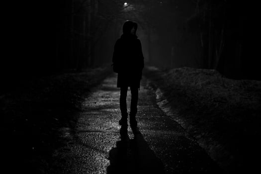 Silhouette of man at night in park. Man walks alone on road in evening. photo