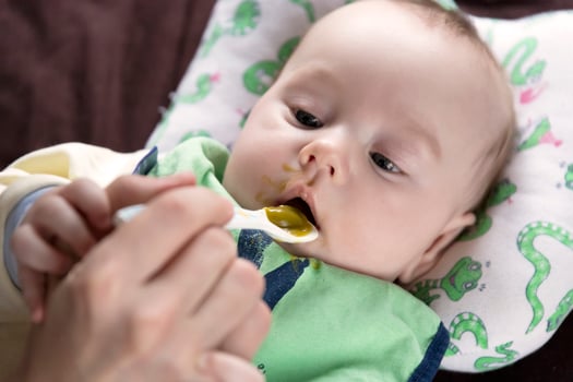 The child, feeding from the first spoon, tastes vegetables for the first time, emotions. photo