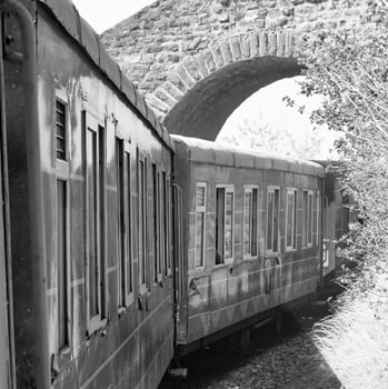 Toy Train moving on mountain slope, beautiful view, one side mountain, one side valley moving on railway to the hill, among green natural forest.Toy train from Kalka to Shimla in India-Black and White photo