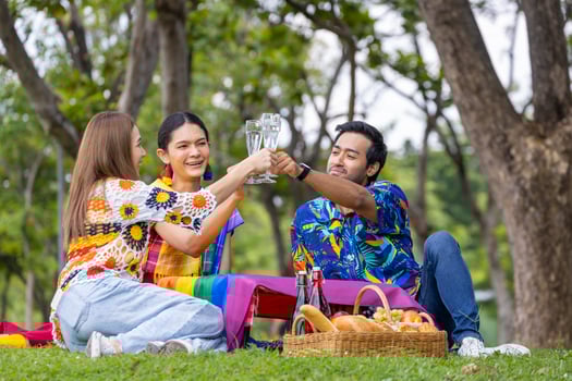 Group of transgender and homosexual people cheers and celebrating LGBTQ pride month in colorful dress and rainbow flag while picnic in the park concept photo