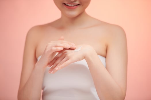 Closeup of female hands applying cream on her arm photo
