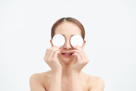 Portrait of a happy woman covering eyes with make up removal pads photo